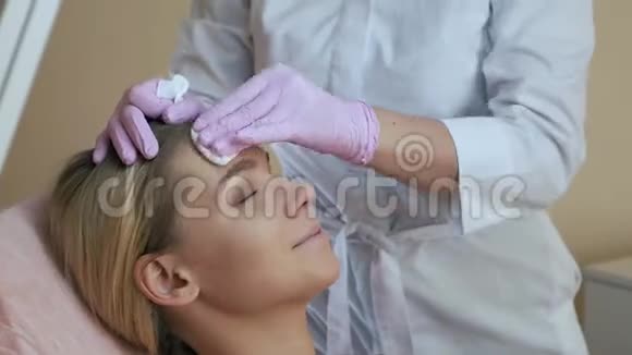 美容师用棉垫擦拭面部为手术做准备视频的预览图