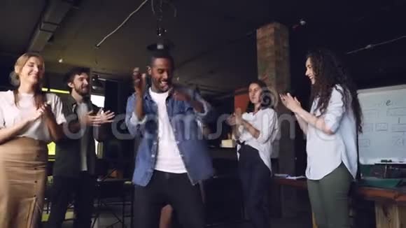 快乐的企业主的缓慢行动非裔美国年轻人在公司聚会上和员工跳舞视频的预览图