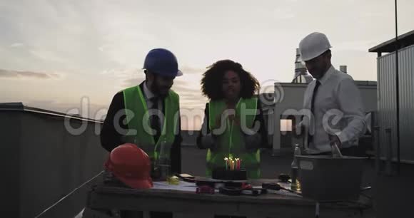 建筑团队庆祝他们的同事非洲族女士从巧克力中吹蜡烛的生日视频的预览图