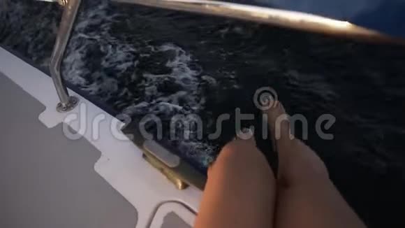一个漂亮的女人她的腿在阳光下慢慢地从游艇上嬉戏地挂在海面上视频的预览图