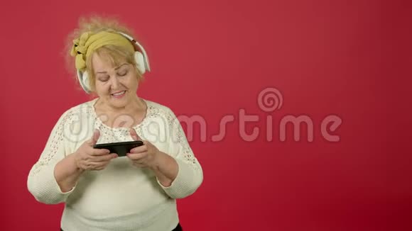 老年超重妇女听耳机音乐和玩智能手机视频的预览图