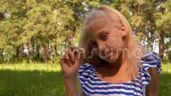 夏天草地上拿着草叶的少女肖像可爱的女孩拿着青草草期待着视频的预览图