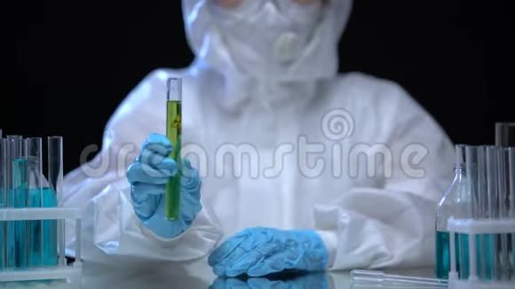 持有绿色电离辐射液体试管的有毒化验室工作人员视频的预览图