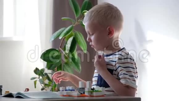 可爱的男孩6岁在家里的桌子上玩五颜六色的塑料玩具砖视频的预览图