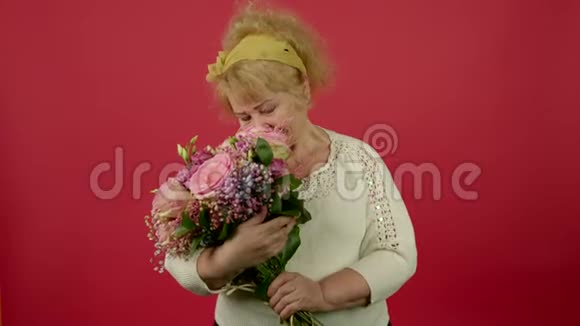 微笑的老年超重女性嗅着花束视频的预览图