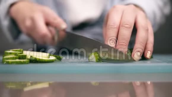 女人的手在切割板上缓慢地切新鲜黄瓜的正面视图把女人的手米色的视频的预览图