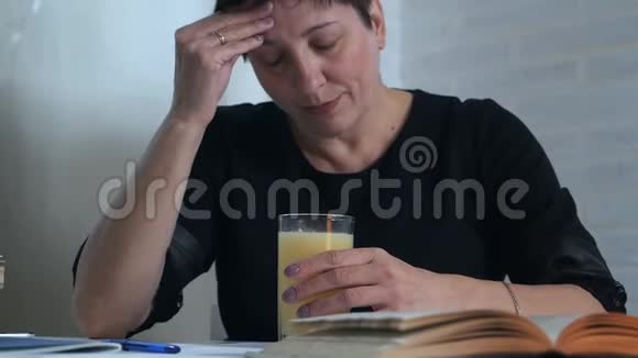 一个穿着黑色衣服的女人坐在一张桌子旁拿着一杯水和维生素来进行大脑活动创意疲劳视频的预览图