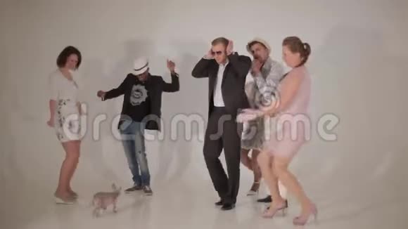 三个可爱的女人和三个迷人的男人在白色的工作室里和小狗跳舞视频的预览图