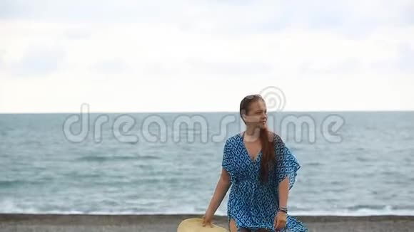 生活方式漂亮的女人带着一顶大帽子在海滩上散步视频的预览图