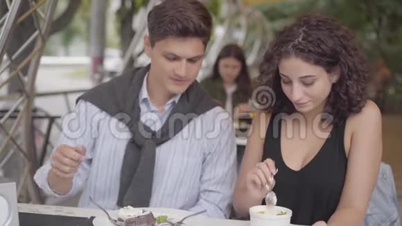 一些男人和可爱的女人坐在户外咖啡馆里吃沙漠的肖像年轻的男女玩得开心视频的预览图