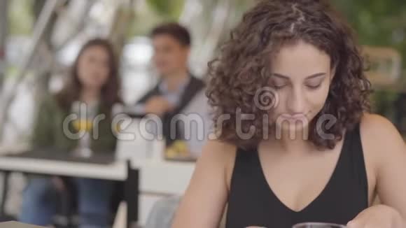 漂亮的年轻卷发女人在街头咖啡馆吃美味的肉菜和土豆在户外享受甜点放松的女孩视频的预览图