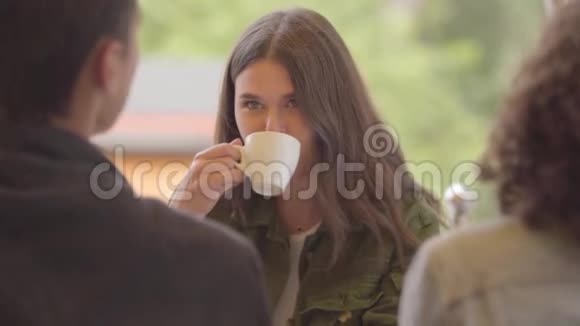 三个朋友一起坐在户外咖啡馆里享受咖啡两个女人和一个男人开会视频的预览图