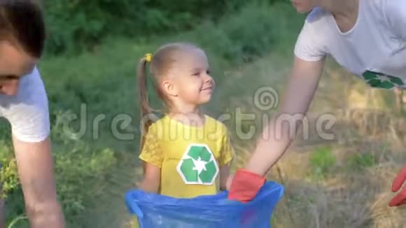 拯救地球年轻的家庭幸福可爱的女孩戴着橡胶手套从大自然的垃圾袋里收集垃圾视频的预览图