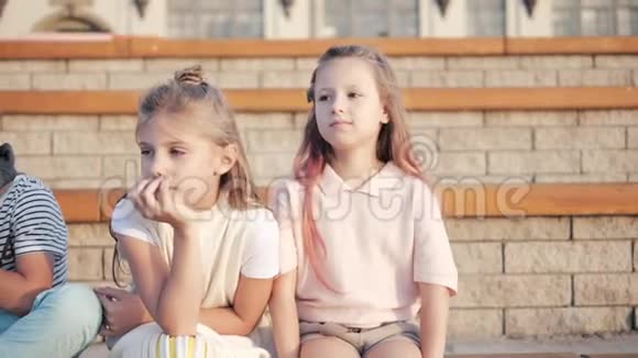 可爱的男孩和女孩坐在公园里视频的预览图