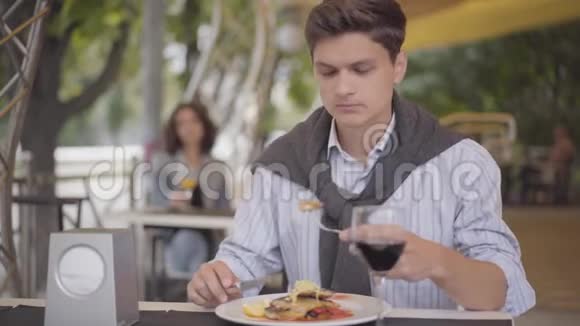 帅哥在街头咖啡馆吃美味的肉喝红酒那个女孩在户外享受他的晚餐放松视频的预览图