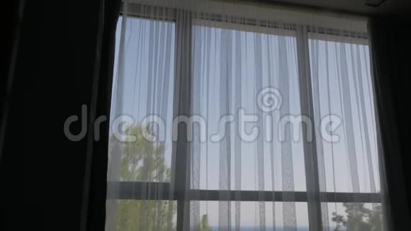 一个穿浴袍的男人的剪影来到酒店房间的一个大窗户前那个人望着窗外欣赏着视频的预览图