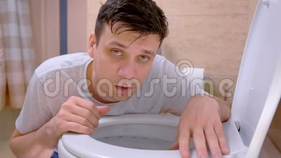 男人呕吐在厕所里坐在地板上看着摄像机感觉不好得流感视频的预览图