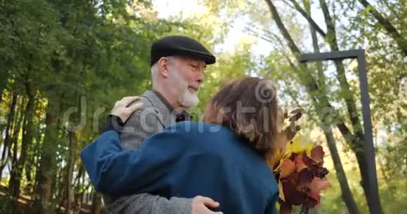 退休后积极的现代生活快乐的老夫妇在秋天美丽的公园的小巷里跳舞慢视频的预览图