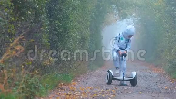 一个穿着宇航员服装的男孩骑着陀螺仪穿过一片雾蒙蒙的森林视频的预览图