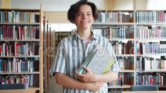 男生在学校图书馆捧书的肖像脸上洋溢着快乐视频的预览图