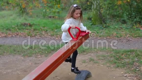 一个穿白衣服的女孩在城市公园里骑着平衡秋千视频的预览图