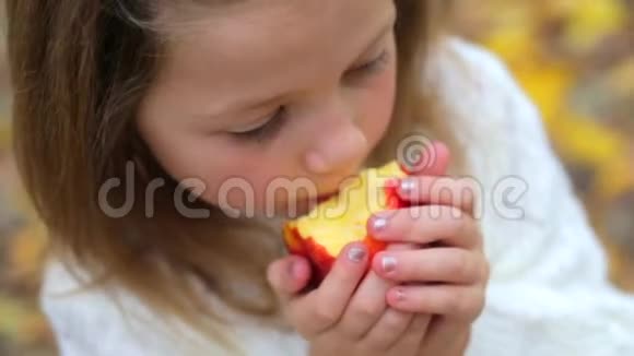 特写镜头一个女孩在秋天的森林里啃一个红苹果视频的预览图
