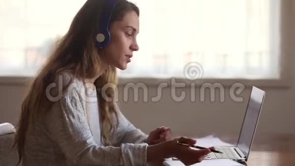 戴耳机的年轻女性使用电脑和电话会议应用程序学习视频的预览图