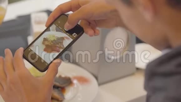 一位年轻人在餐厅用手机拍下他的鱼碟他在享受食物视频的预览图