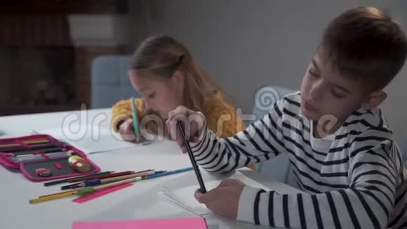 两个白人孩子坐在学校的桌子旁有两个马尾辫的女孩子在练习本上写字视频的预览图