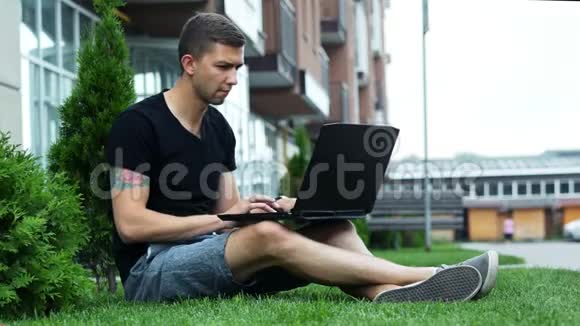 自由职业者坐在草地上在露天工作的笔记本电脑视频的预览图