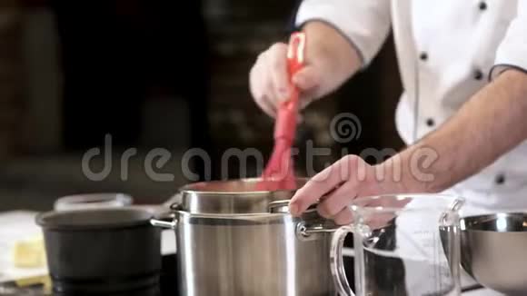 厨师在餐馆厨房准备食物把酱汁混合在炉子上的平底锅里视频的预览图