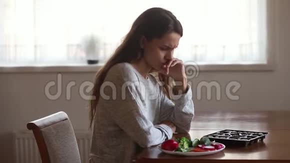 坐在餐桌前的女孩决定吃糖果或蔬菜视频的预览图