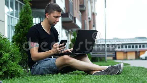 年轻人坐在草地上使用手机和笔记本电脑视频的预览图