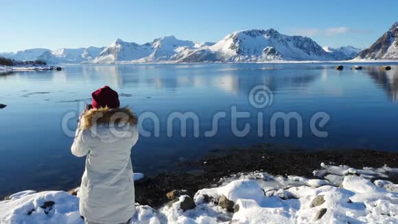 女孩在阳光明媚的冬季峡湾拍照视频的预览图