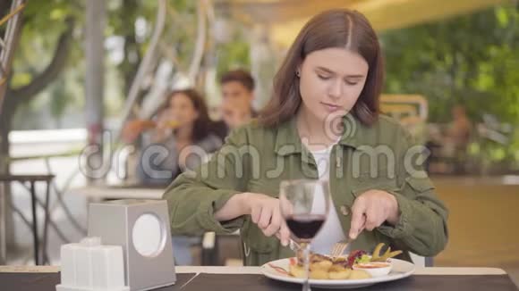 年轻的美女在街头咖啡馆里吃着美味的肉菜和土豆喝着红酒喜欢放松的女孩视频的预览图