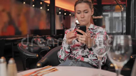 有魅力的白种人女性坐在餐馆里使用手机等待订单的概念慢慢视频的预览图
