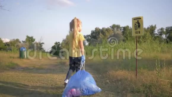 停止污染可爱的小女孩根据垃圾桶上的指示牌在路上拉着一个带垃圾的大垃圾袋视频的预览图
