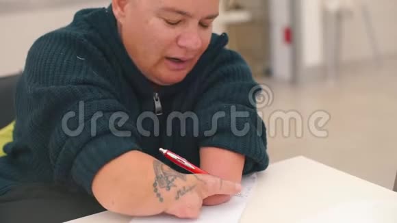 残疾妇女在办公室的一张桌子上用钢笔写文字视频的预览图
