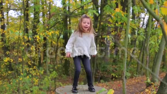 欢乐的女孩在秋天的森林里跳舞当场跳跃视频的预览图