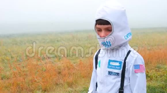 一个穿着白色西装戴着面具的男孩在一片雾气弥漫的田野里视频的预览图