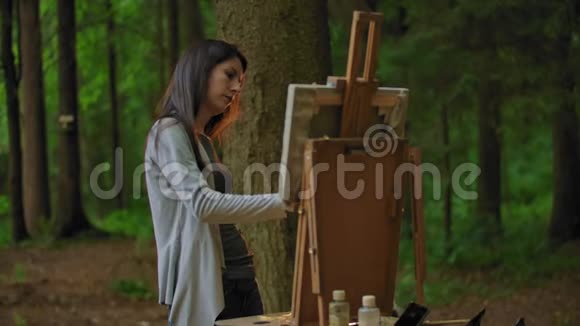 一位年轻女子在公园里画风景的侧景视频的预览图