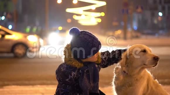 对宠物的爱小男孩在傍晚城市的户外抚摸他的狗视频的预览图