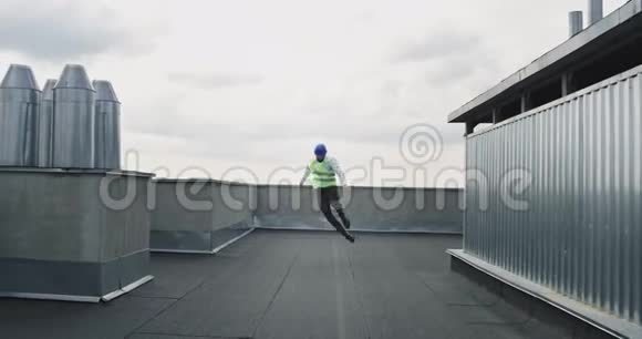 屋顶上的现代建筑工地有魅力的建筑师或工程师戴着安全帽在前面兴奋地跳舞视频的预览图