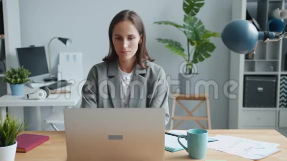 一幅美丽的女商人在办公桌上拿着笔记本电脑忙着工作的画像视频的预览图