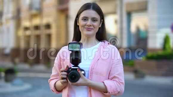微笑的年轻女子站在城市街道上带着相机上摄影课视频的预览图