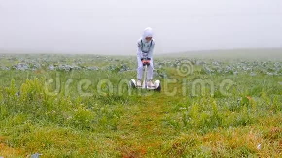 一个穿着白色西装的男孩骑着一个陀螺仪在一片大雾的田野上视频的预览图