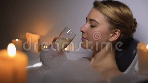 梦中的女人躺在浴缸里泡着泡沫和蜡烛喝着香槟视频的预览图