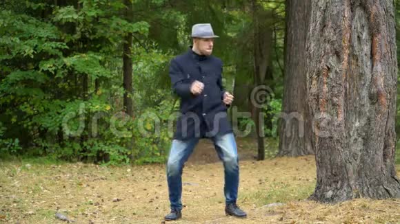 一个戴着帽子和外套的商人在树林里快乐地搬家视频的预览图