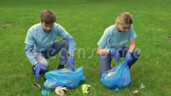 男女志愿者在公园里捡垃圾互相微笑生态视频的预览图