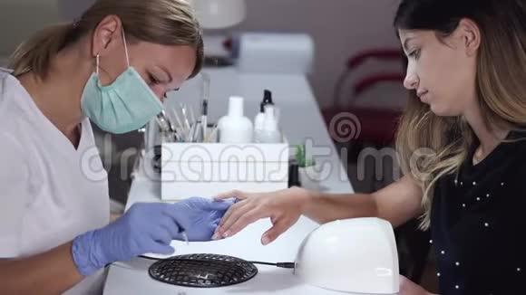 戴面罩的指甲师傅为美容院的女人修指甲视频的预览图